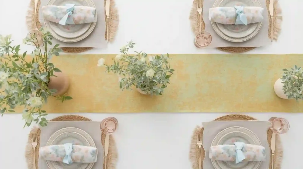 Soft yellow and mint gradient table runner with woven placemats and greenery, illustrating vibrant spring tablescape tips for a top-down view.