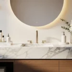 Modern bathroom vanity decor with marble countertop, gold faucets, backlit round mirror, and stylish greenery.